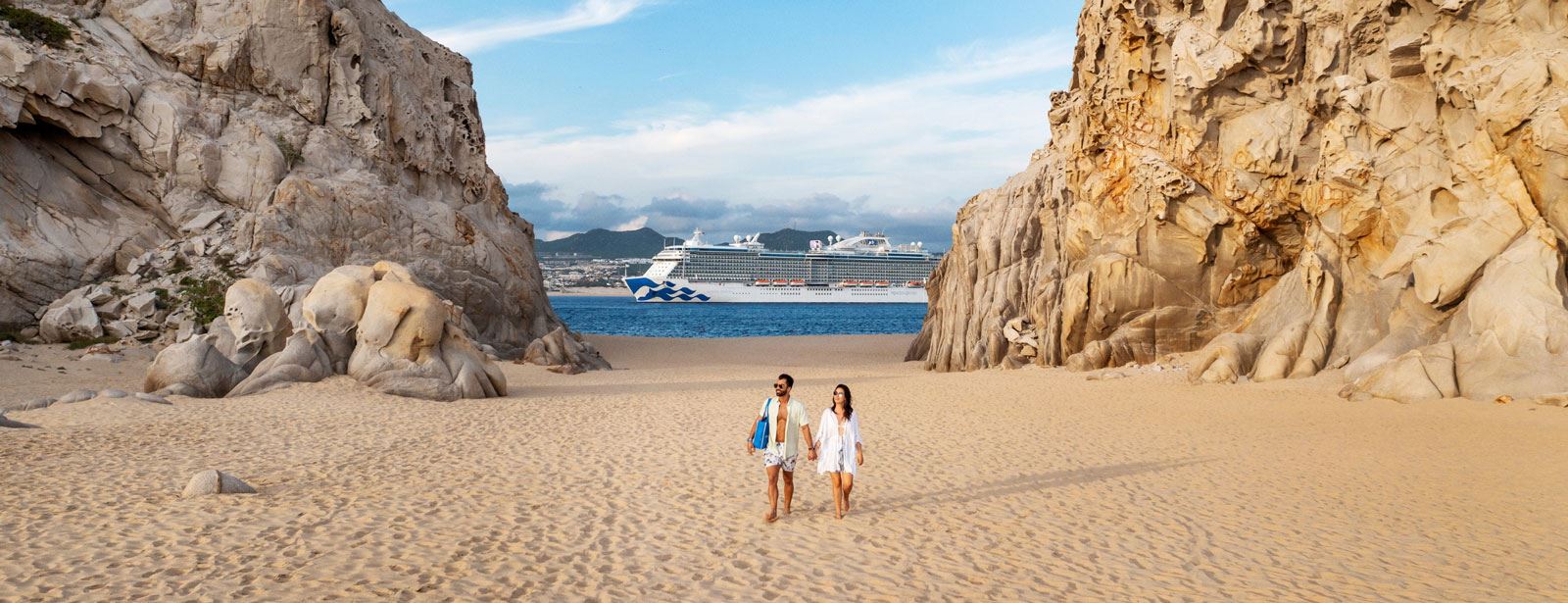 Couple on beach with Princess cruise ship in background of rocky shore
